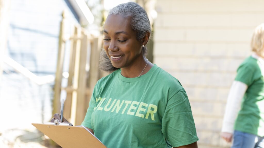 Retirees: Doing What You 'Ought' Beats Doing What You Want An older woman wearing a T-shirt that says "volunteer" looks at a clipboard.
