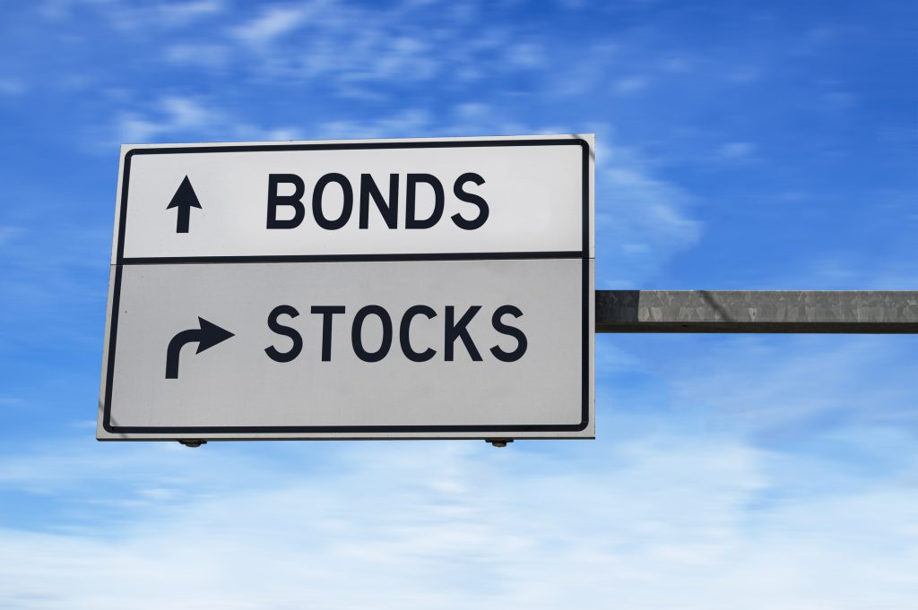 The 100 Minus Your Age Rule: Is It the Best for You? A white road sign with the word bonds next to an arrow pointing straight ahead and the word stocks next to an arrow pointing to the right.