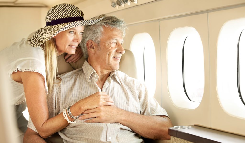 The Smart Way to Retire: 13 Habits to Steal From the Wealthy A wealthy older couple on a private plane, looking out the window.