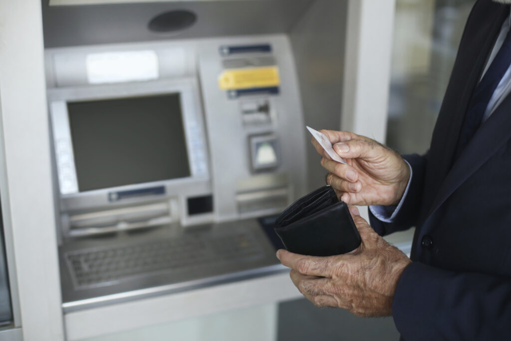 Think Twice Before Getting a Credit Card Cash Advance A man pulls a card from his wallet while standing in front of an ATM.