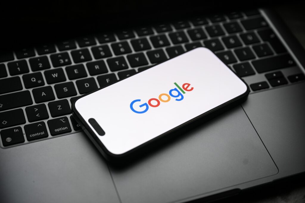 $425 Million Google Class Action Lawsuit: Do You Qualify for a Payout? The Google logo displayed on a smartphone that's sitting on top of a laptop.