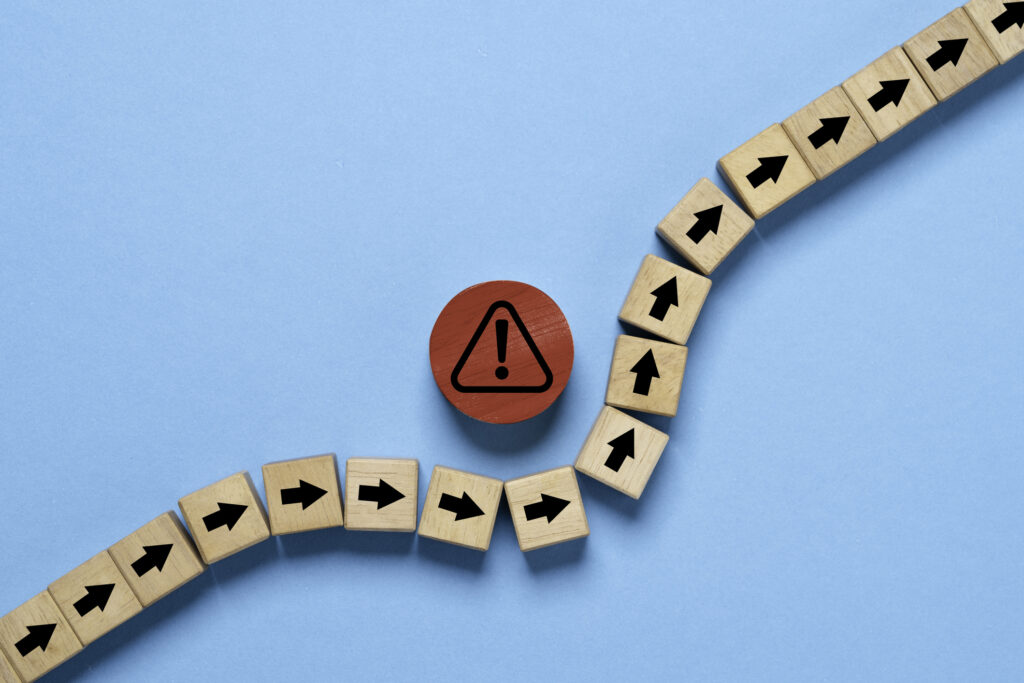 7 Mistakes to Avoid When You First Start Investing red circle block with red exclamation warning sign in the middle of a line of wooden blocks with black arrows