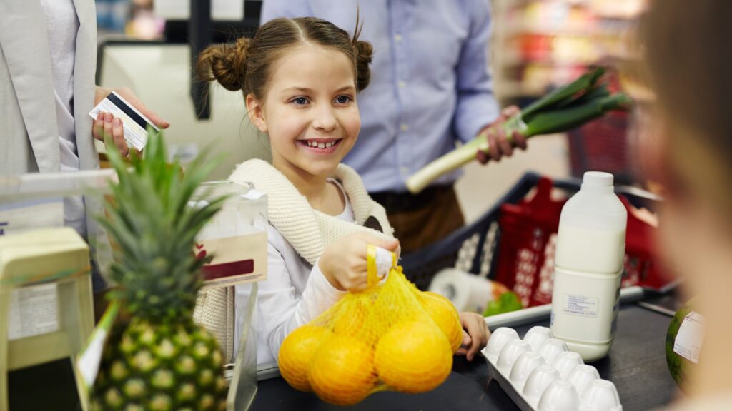 A Tale of Forgotten Change and Compassion at the Supermarket A young girl holds a bag of lemons at the checkout counter of a supermarket.