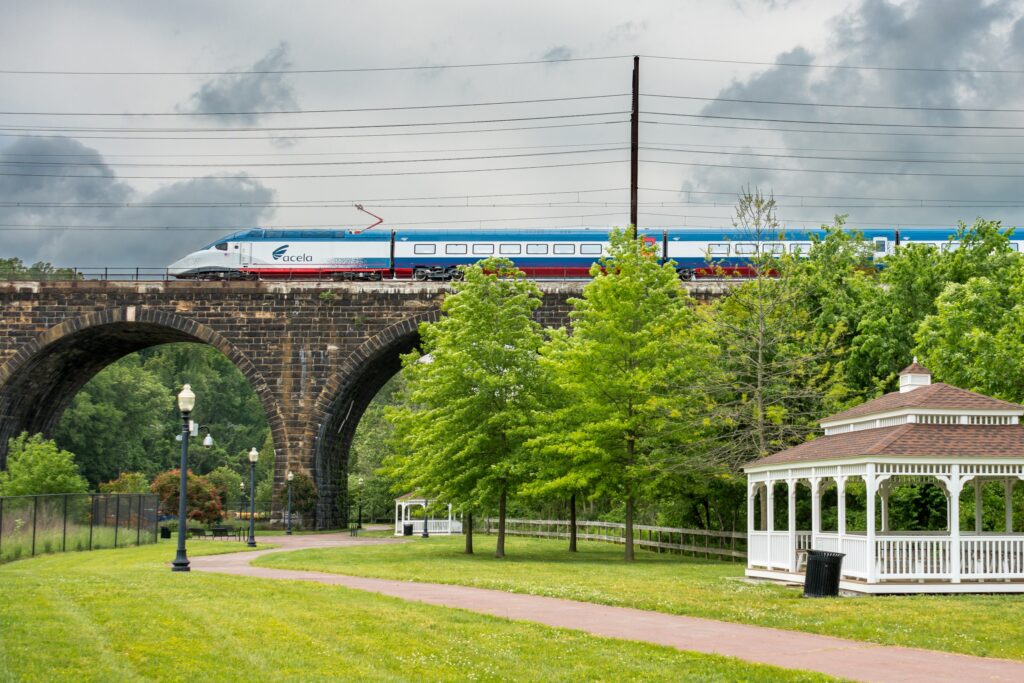 An Amtrak Acela train going over a bridge in a town.