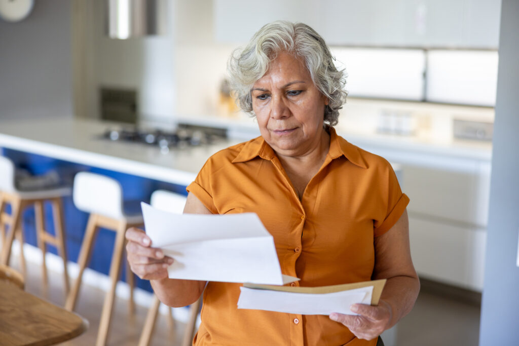 Senior Latin American woman at home reading a letter she got in the mail â€“ domestic life concepts