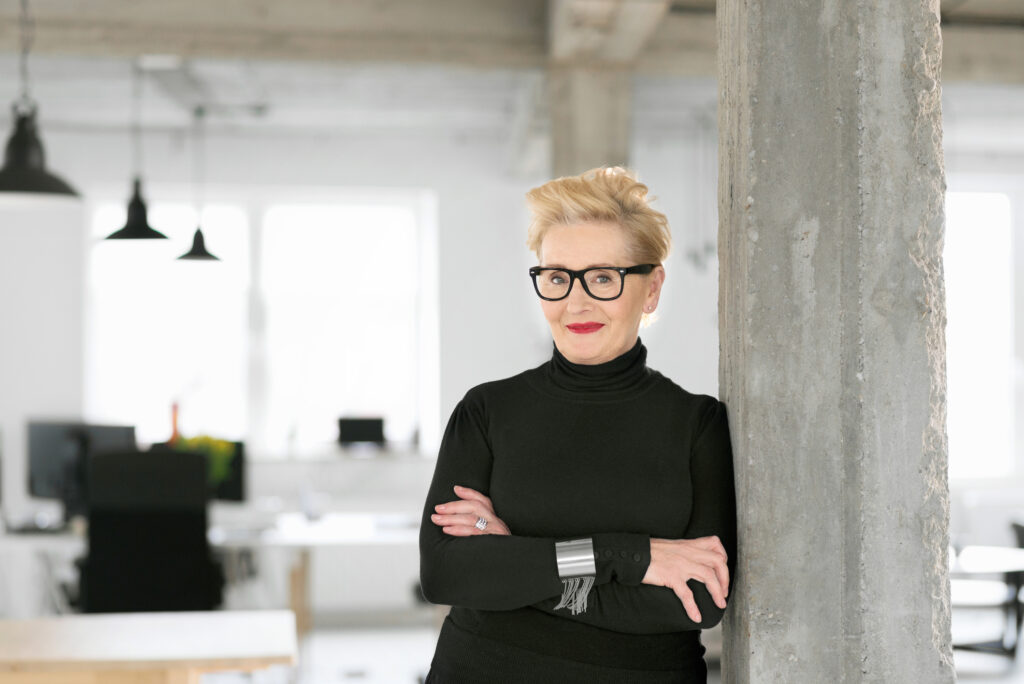 Portrait of elegant older businesswoman standing in the modern studio, smiling at the camera.