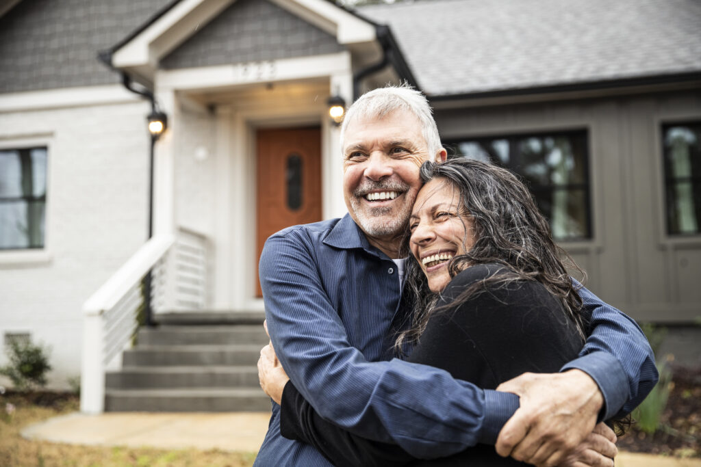 How a mortgage underwriter impacts the home buying process A couple embracing in front of their new home