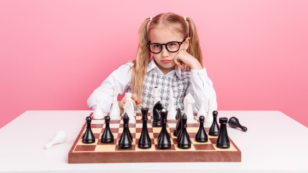 A young girl projects a challenging look while sitting behind a chessboard.