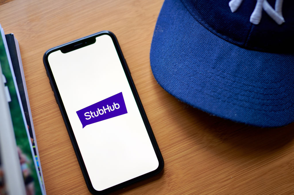 StubHub IPO: Should You Buy STUB Stock? The StubHub logo on a smartphone on a table next to a New York Yankees baseball hat