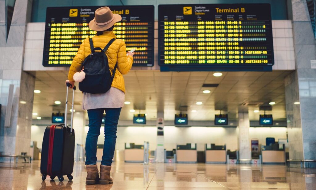 Young woman at the airport in Barcelona checking for the flight schedule